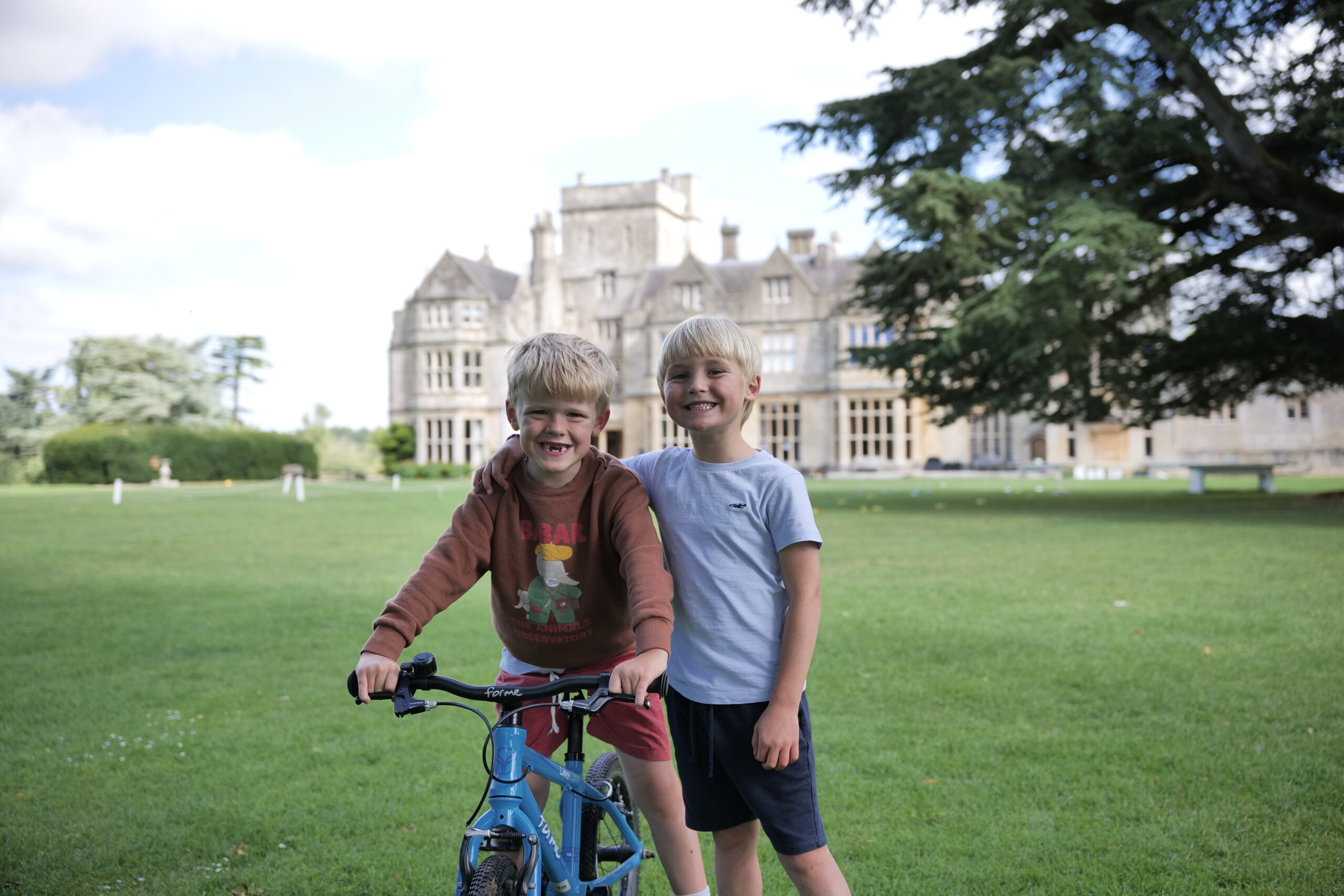 Boy riding a bike with another boy smiling at the camera